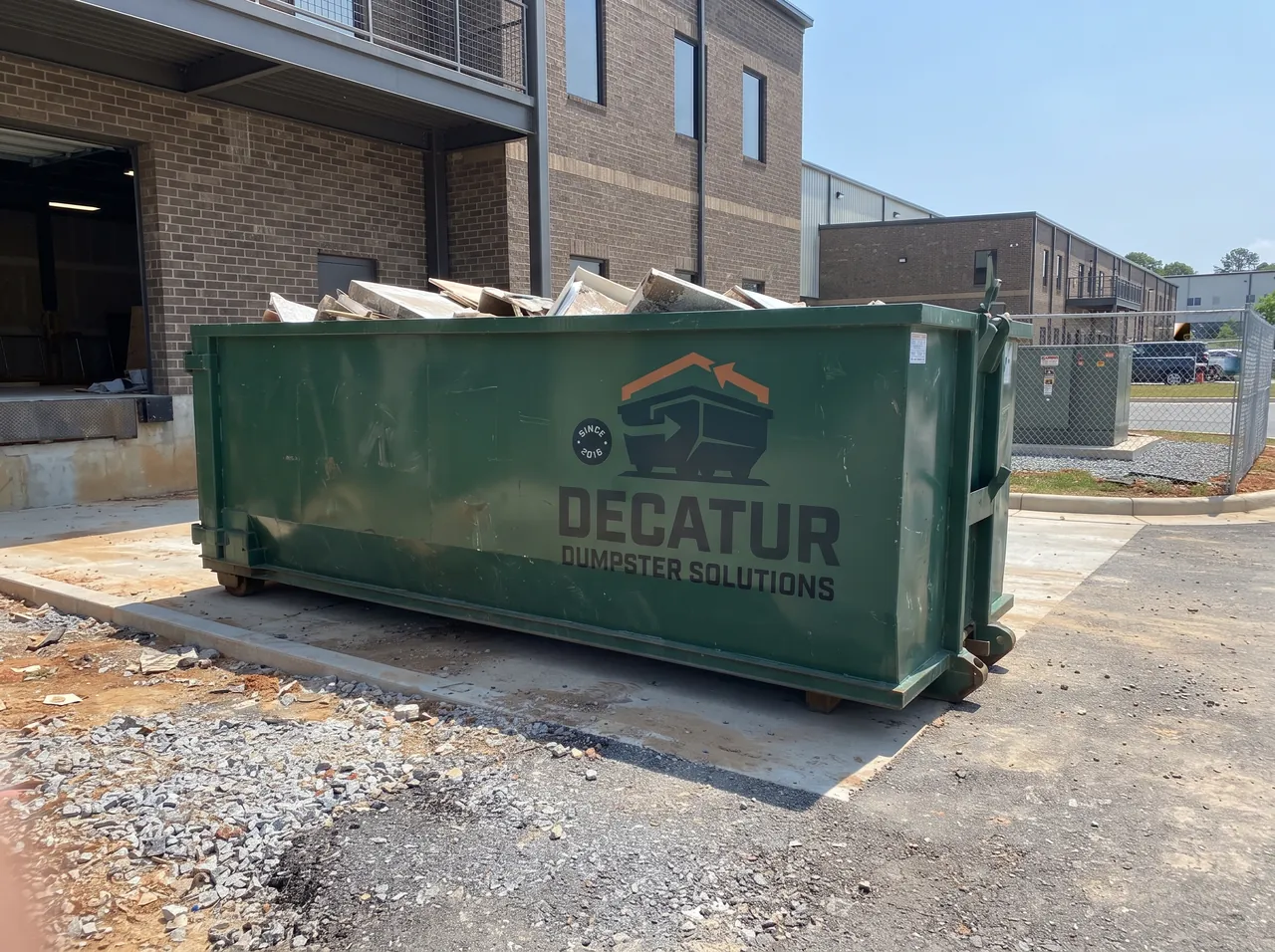 Green roll-off dumpster on a residential property used for heavy concrete and debris removal